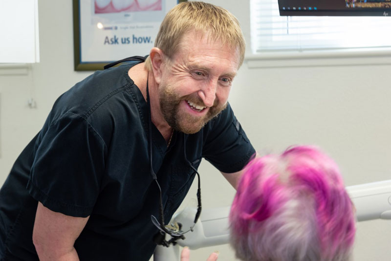 Smiling dentist speaking with a senior patient during a dental consultation in Albuquerque NM.